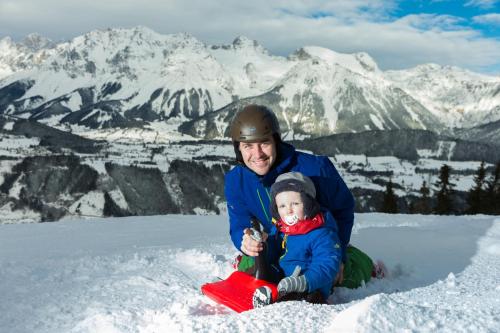 a man and a child sitting in the snow at Appartement Klosterhügel in Haus im Ennstal
