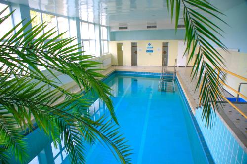 a swimming pool in a building with a palm tree at Gemütliches Studio mit Ausblick, Pool und WiFi in Baiersbronn