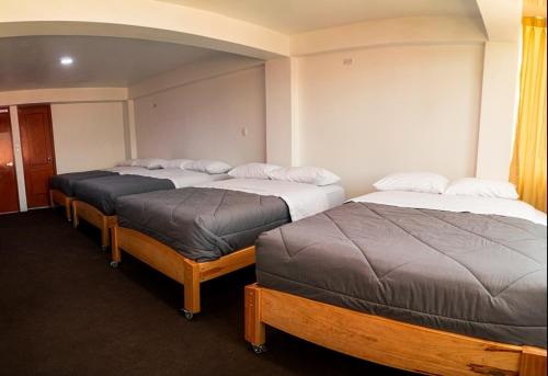 a room with three beds in a room at Alpino Guest House in Huaraz