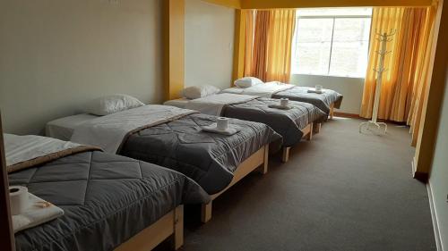 um grupo de quatro camas num quarto em Alpino Guest House em Huaraz