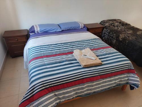 Una cama con una manta a rayas y un bolso en ella en DEPARTAMENTO CON COCHERA ( COMPLEJO FRENCH ), en La Rioja