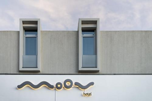 two windows on the side of a building with a sign at Moov Hotel Évora in Évora