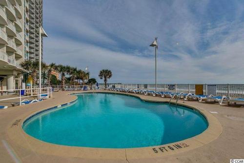 a large blue swimming pool with chairs and a building at Gorgeous Condo 3 Br 3 Balconies SB 11th Floor in Myrtle Beach