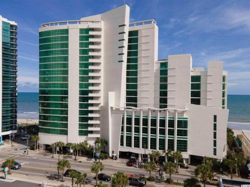 a large white building with green windows next to the ocean at Gorgeous Condo 3 Br 3 Balconies SB 11th Floor in Myrtle Beach