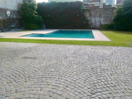 una piscina en un patio con una entrada de ladrillo en Ocio Quesada en Buenos Aires