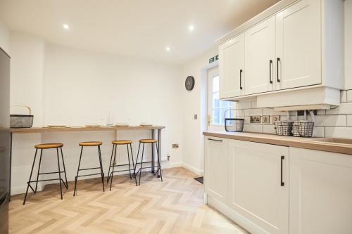 a kitchen with white cabinets and bar stools at Luxurious and Modern 3 Bed townhouse with Parking in Norwich