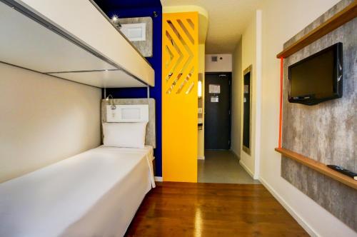 a room with a bed and a tv and a hallway at ibis budget Tambore in Barueri