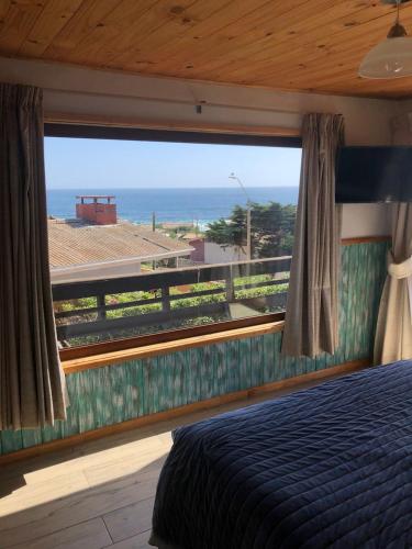 a bedroom with a bed and a view of the ocean at Hostal F in El Quisco