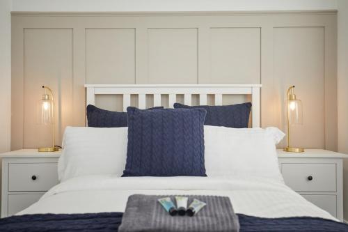 a bedroom with a white bed with blue pillows at Luxurious and Modern 3 Bed townhouse with Parking in Norwich