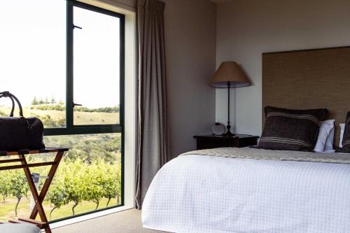 a bedroom with a bed and a large window at Vineyard Apartment in Tutukaka