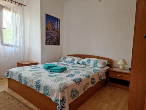 Schlafzimmer mit einem Bett mit einer blauen und weißen Bettdecke in der Unterkunft Apartment Opaćac Veli Iž in Veli Iž