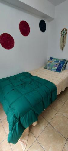 a bed with a green comforter in a room at Private Cozy room with batroom in Miraflores in Lima