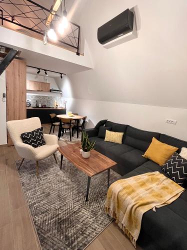 a living room with a black couch and a table at Klek 77 Luxury Chalets near Jahorina in Paočići