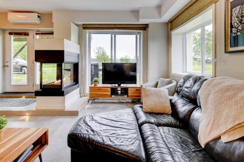 a living room with a leather couch and a flat screen tv at Nouveau - Bord de fleuve, Mont Sainte-Anne et + ! in Sainte-Anne-de-Beaupré
