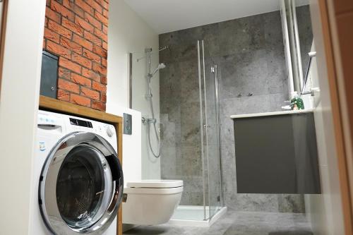 a bathroom with a shower and a washing machine at HALO Apartament 07 in Wrocław