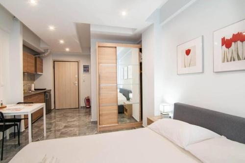 a bedroom with a white bed and a kitchen at Cozy Studio, Athens city center in Athens