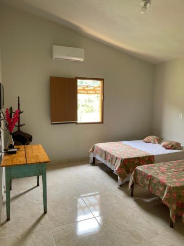 1 dormitorio con 2 camas, mesa y ventana en Chalé da Picareta en São Roque de Minas