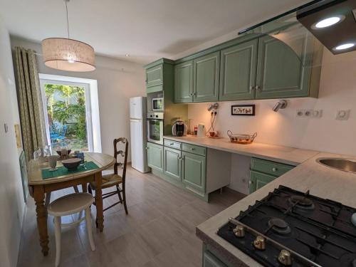 - une cuisine avec des placards verts, une table et une cuisinière dans l'établissement Maison charmante avec terrasse, jardin clos, barbecue, près de la Charente - 3 ch, 2 sdb - FR-1-653-31, à Bassac