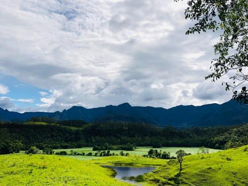 a river in a field with mountains in the background at Fazenda São Matheus in Louro Müller