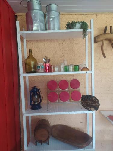 a white shelf with red plates and shoes on it at Fazenda São Matheus in Louro Müller