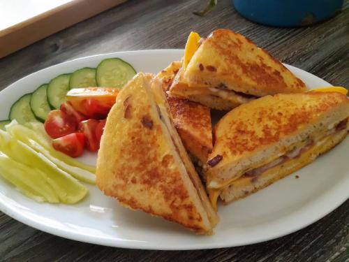 Un plato blanco con un sándwich a la parrilla y verduras. en Kiskemence Vendégház Szatta, en Szatta