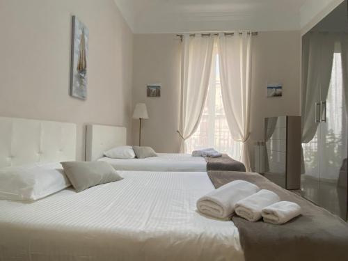 duas camas num quarto branco com toalhas em A casa da Carlo em Palermo