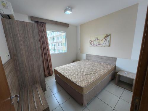 a small bedroom with a bed and a window at Prive Riviera - Apartamentos JN in Caldas Novas