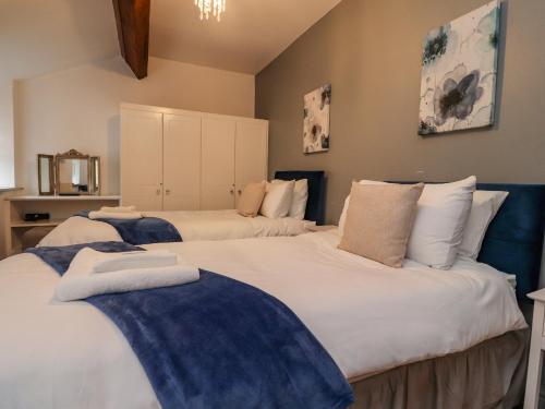um quarto com 2 camas com almofadas azuis e brancas em Noah's Barn em Poulton le Fylde