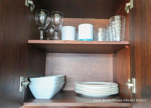 a cabinet with plates and wine glasses and bowls at Costa Bonita Private Villas in Culebra