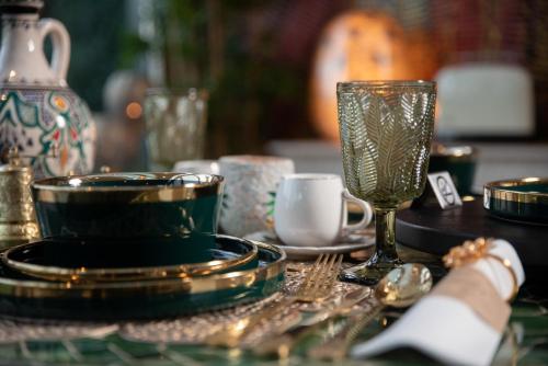 a table with plates and cups and a glass at B&B 1001 nacht in Zonhoven