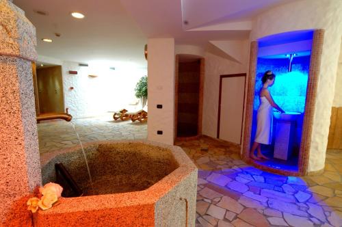 Una mujer parada en un baño con bañera en Carlo Magno Hotel Spa Resort, en Madonna di Campiglio