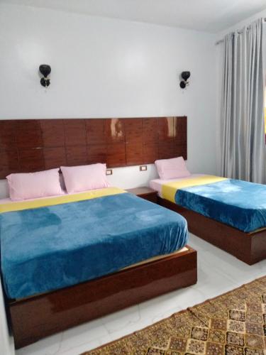 a bedroom with two beds with blue and yellow sheets at Jamaica Guest House in Aswan