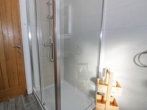 a shower with a glass door in a bathroom at Y Caban in Cemaes Bay