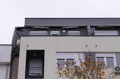 a white building with a black roof at Green and grey in Novi Sad