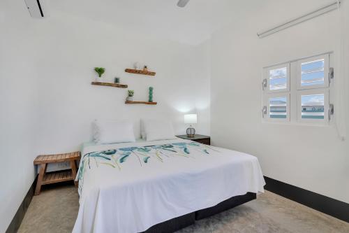a white bedroom with a bed and a window at Blue Breeze Apartment in Water Villas in Kralendijk
