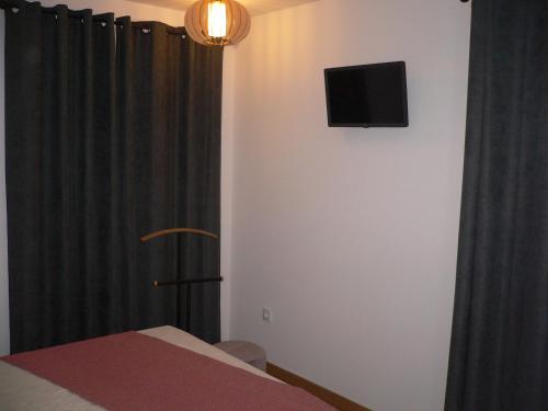 a room with a tv on the wall and a curtain at Maria João in Paredes de Coura