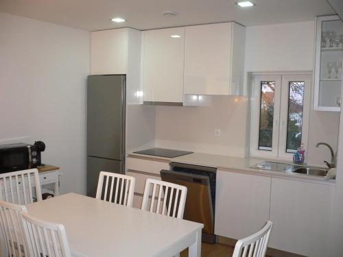 a kitchen with white cabinets and a table and chairs at Maria João in Paredes de Coura