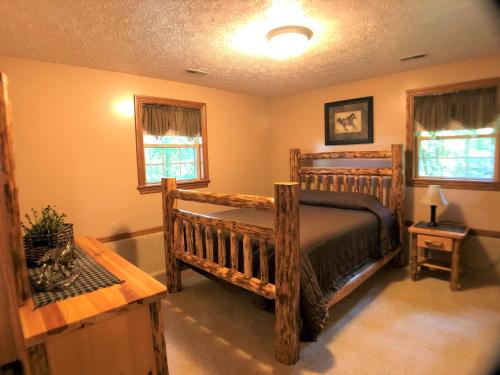 a bedroom with a wooden bed and two windows at Sojourner's Lodge & Log Cabin Suites in Dundee