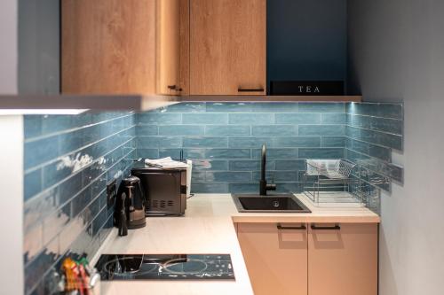 - une cuisine avec du carrelage bleu sur le mur dans l'établissement Deluxe Dunavska Apartment 4, à Novi Sad