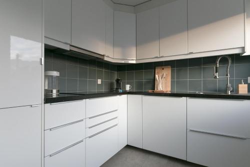a kitchen with white cabinets and black counter tops at INN JOY Apartments - Rorschach mit Panoramasicht in Rorschach
