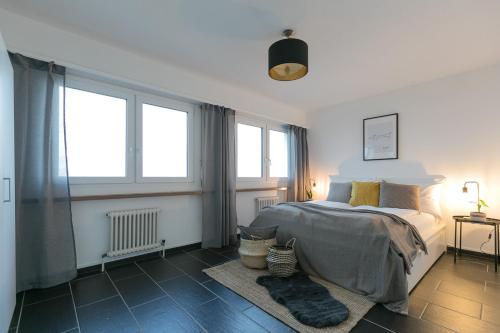 a bedroom with a bed and two windows at INN JOY Apartments - Rorschach mit Panoramasicht in Rorschach