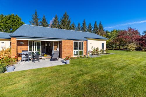 a brick house with a patio and a yard at The Meadows Villa in Christchurch