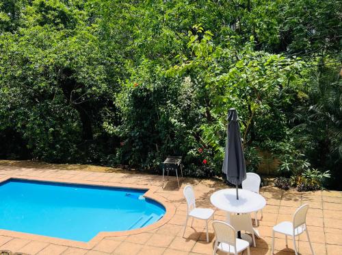 una piscina con tavolo, sedie e ombrellone di Modern Luxury 3 bedroom house a Durban