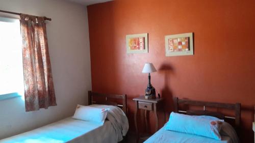 Duas camas num quarto com paredes cor de laranja em Casa en Potrero de Garay em Potrero de Garay