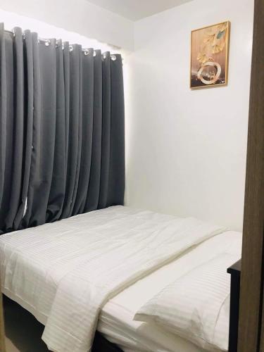 a bedroom with a bed and a window with blue curtains at Shawnalyn Condo-tel at Mall of Asia Philippines in Manila