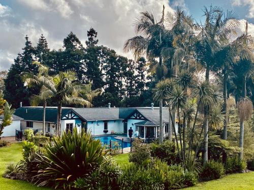 a house with a swimming pool and palm trees at The Bridge House with private pool and jetty in Mangonui