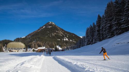 two people skiing down a snow covered road with a mountain at AlpenGold Hotel Davos in Davos