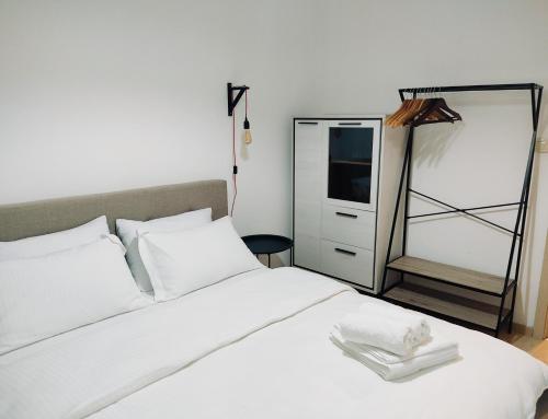 een slaapkamer met een wit bed en een spiegel bij Vista City Apartment in Podgorica