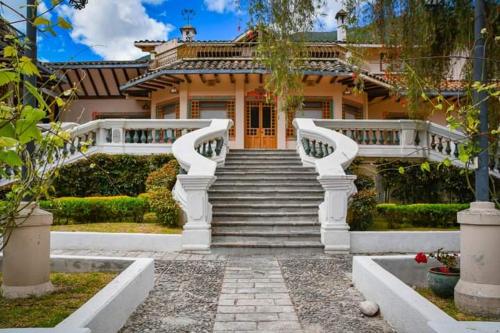 une grande maison avec un escalier en face de celle-ci dans l'établissement Uzhupud Garden Hotel & Lodge, à Paute