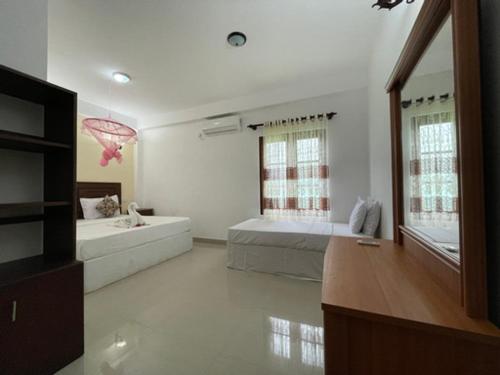 a large room with two beds and a bath tub at ilamparuma Hotel in Weligama